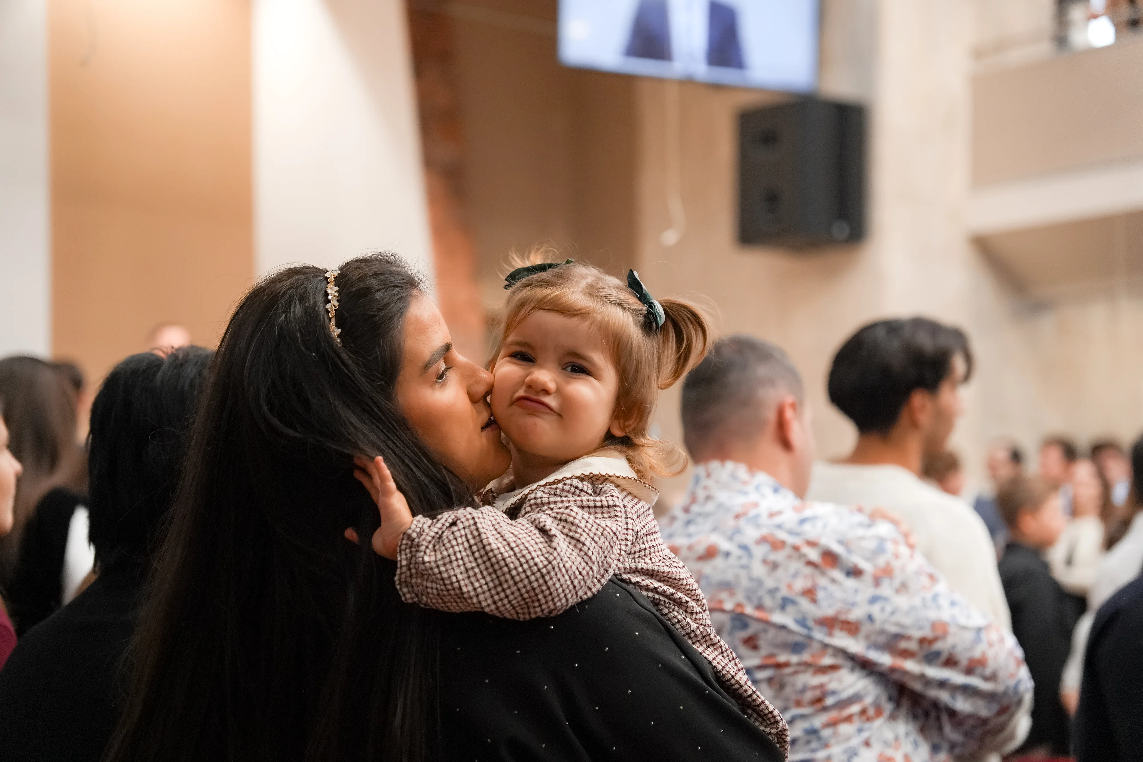 O mamă își sărută fetița în brațe, în sala Bisericii Elim