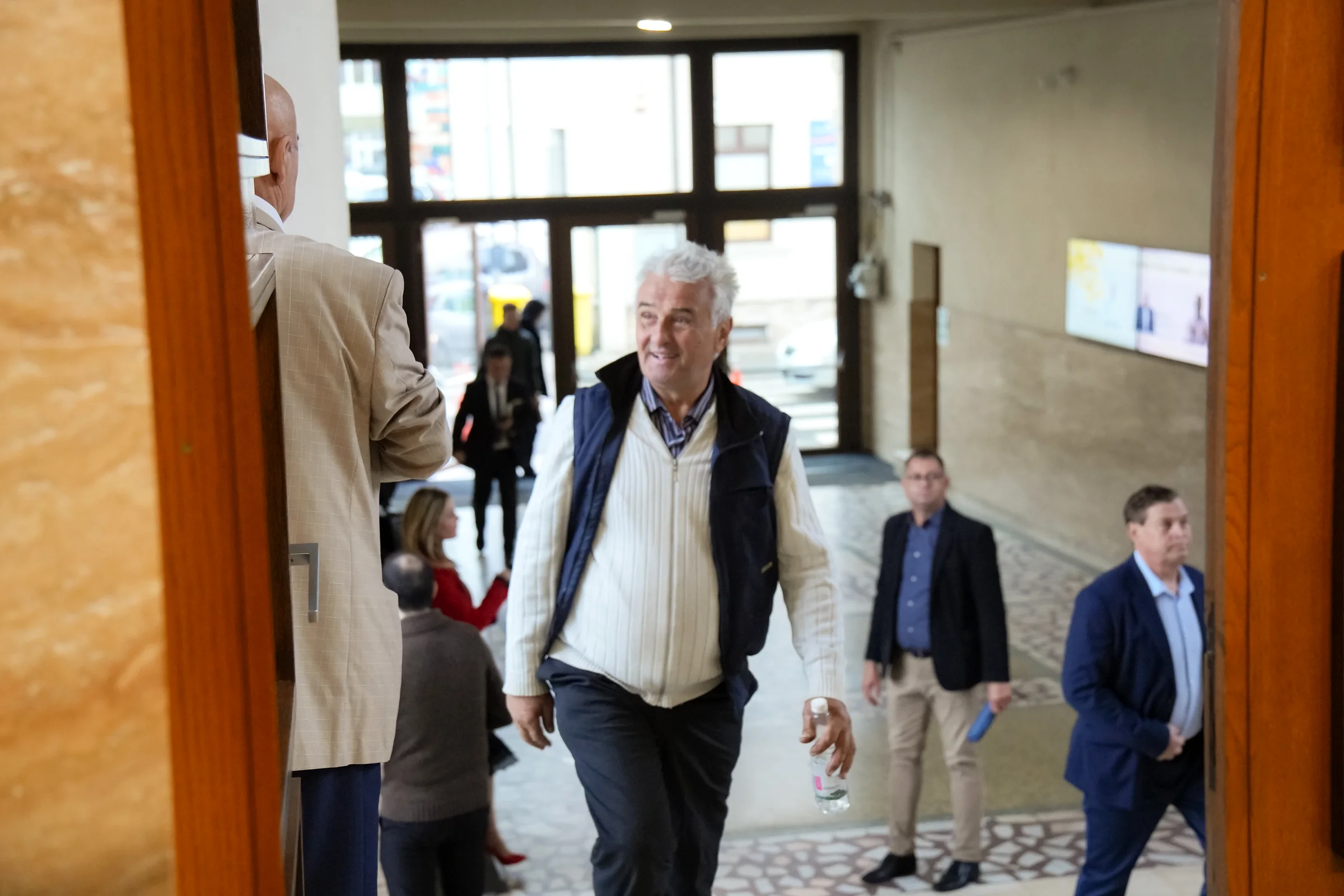 Un bătrân intră zâmbind în Biserica Elim, pe ușa laterală